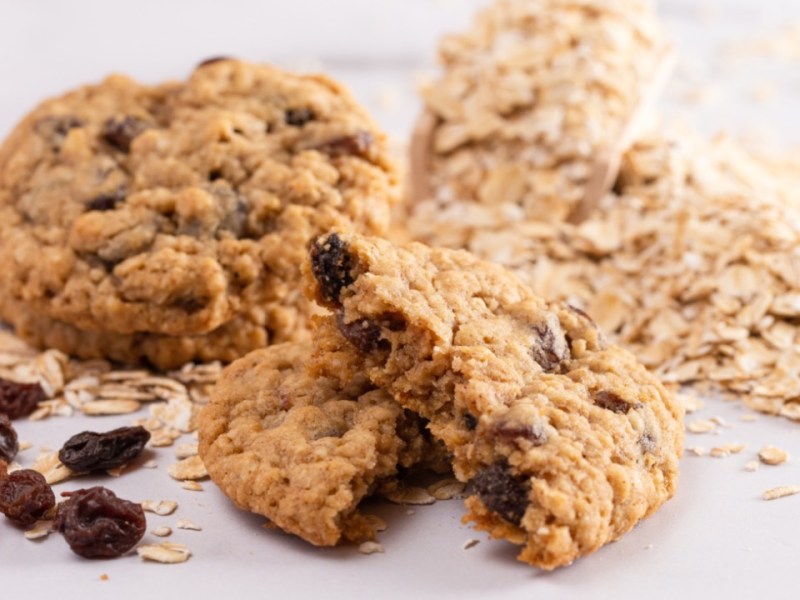 Multiple sugar-free oatmeal cookies with yogurt and raisins. Ingredients are also visible.