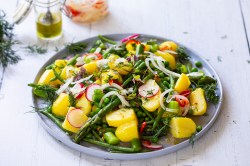 Plate with asparagus and potato salad on a light table