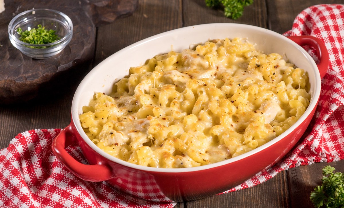 A casserole dish with Chicken Noodle Casserole on a white and red checkered tablecloth