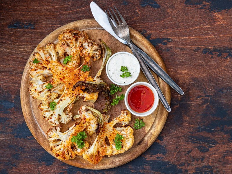 Grilled cauliflower steaks with dips on a board