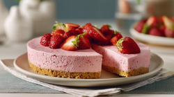 A no-bake skyr strawberry cake is arranged on a plate. One piece is cut.