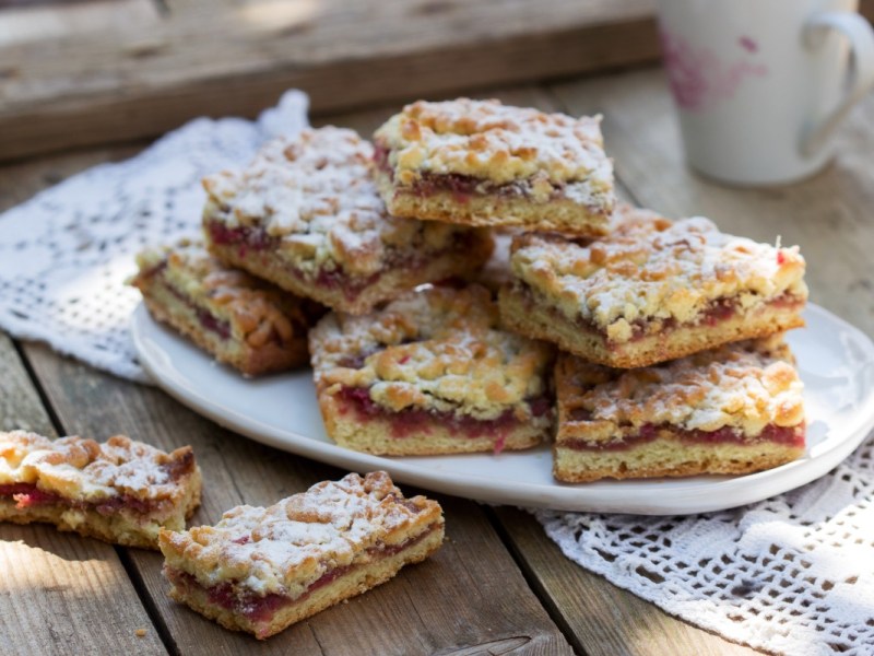 A stack of red berry bars with powdered sugar on a plate.
