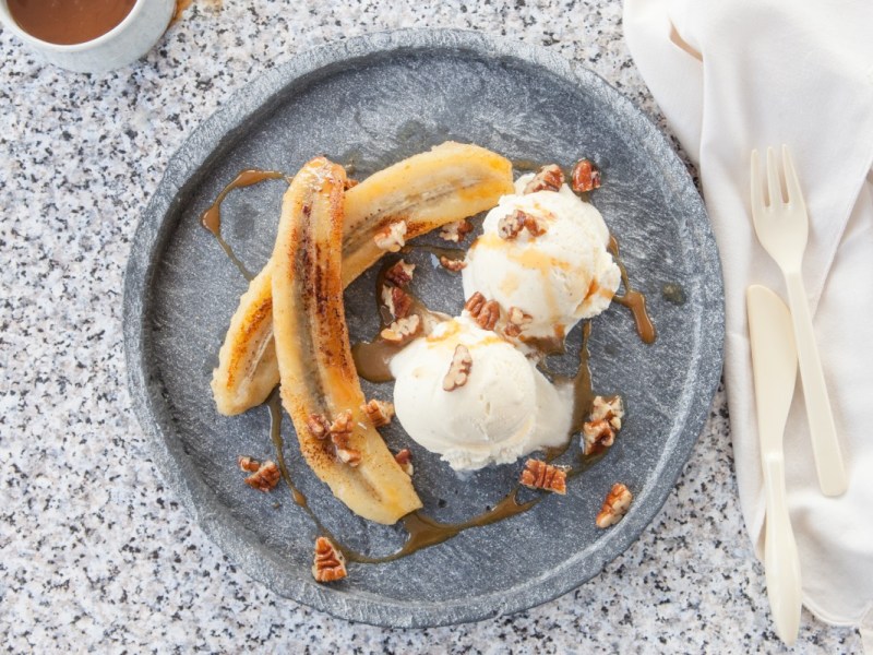 Grilled banana with walnuts and vanilla ice cream on a plate. Top view.