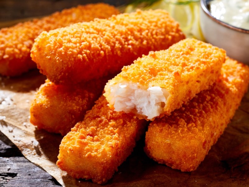Some homemade fish sticks. A bowl of dip in the background.