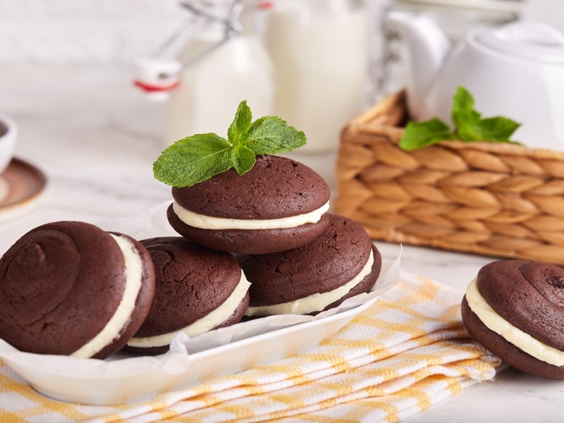 Several whoopie pies on a plate, surrounded by some tableware.
